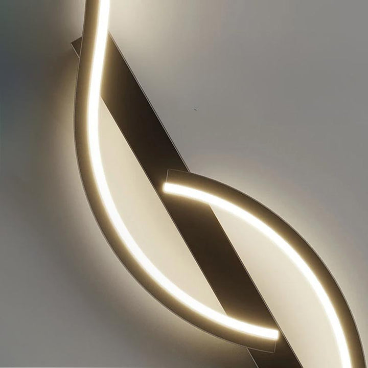 Curved LED wall lamp with matte black base and warm white glow, elegant detail of Nordic-style fixture