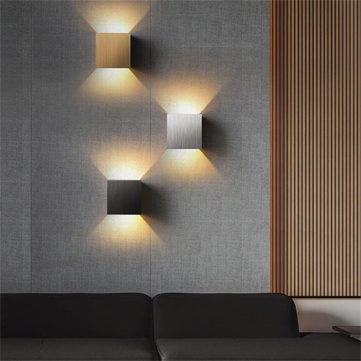 Modern LED wall lights on a grey wall with a black sofa and wooden panel in the background