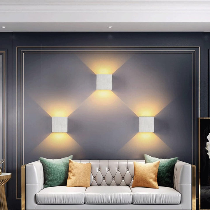 Modern living room with a gray sofa, decorative pillows, and wall lights.