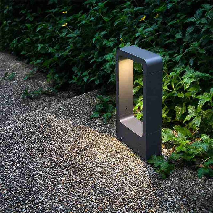 Modern outdoor LED ground lamp in sleek rectangular frame, dark grey finish, lighting garden pathway with warm glow.