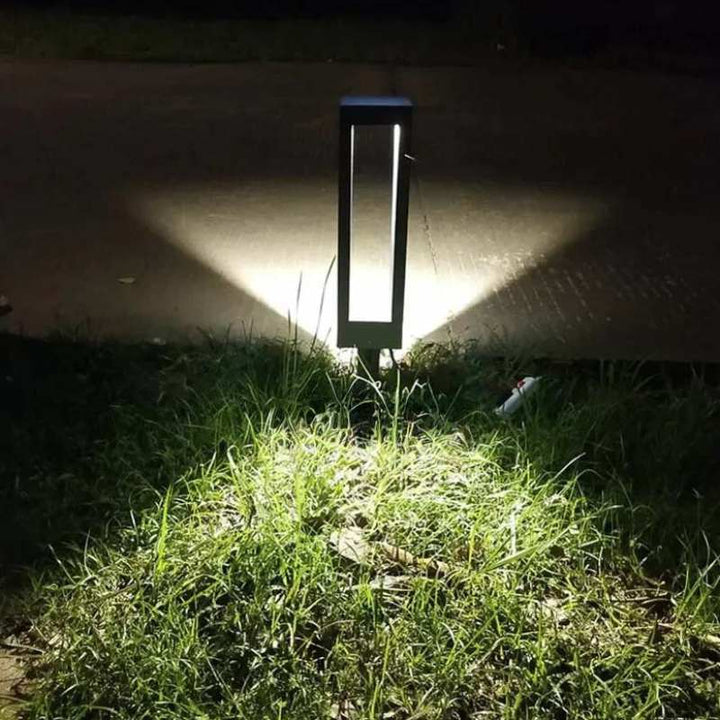 Solar-powered outdoor light fixture illuminating grass at night