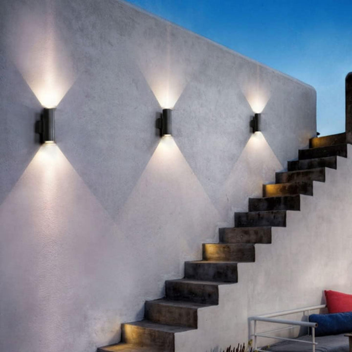 Modern staircase with wall-mounted lights against a concrete wall.