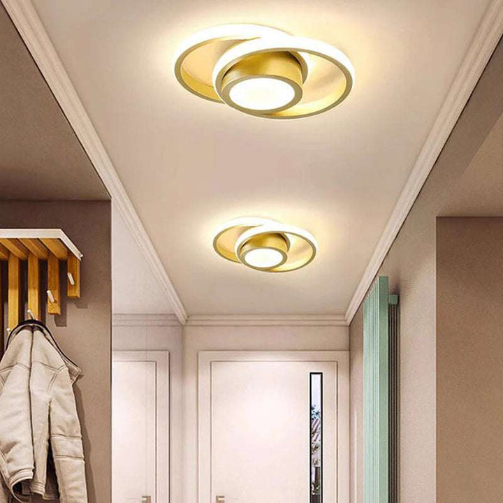 Golden double ring LED ceiling lights illuminating a modern hallway interior