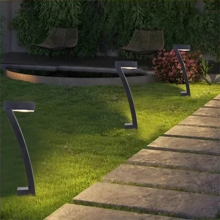 Modern black 7-shape solar garden light in lush green garden, casting warm LED light on pathway