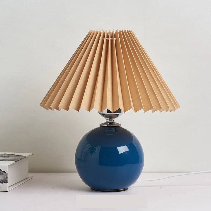 Deep blue ceramic lamp with folded paper-style pleated shade, ideal for UK reading corners or nightstands.