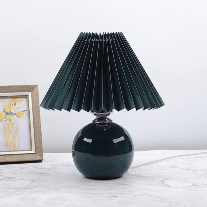 Modern green table lamp with black pleated fabric shade, bold accent lighting for stylish interiors.