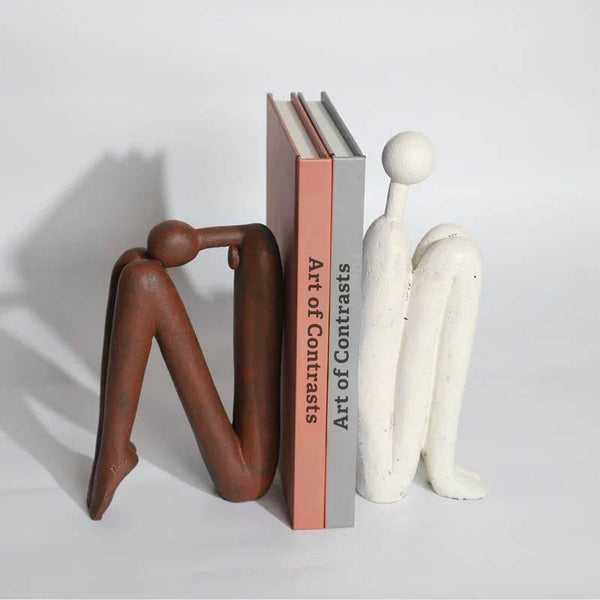 Modern Thinker Bookends Supporting Books on Shelf – White and brown resin thinker statues used as bookends, providing stable support for books while enhancing shelf aesthetics in a study or living ro
