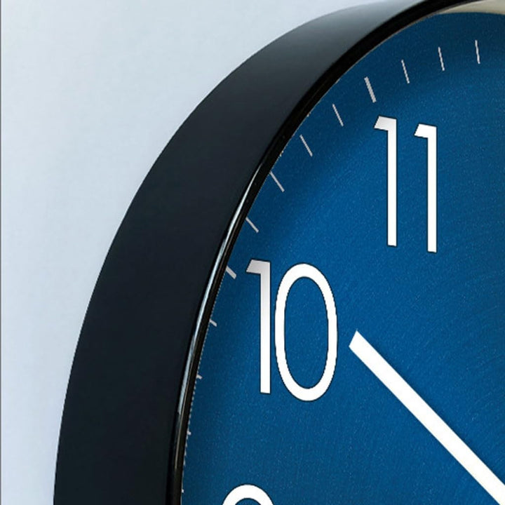 Close-up of a blue wall clock with black frame on a light grey background