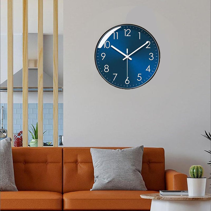 Blue modern wall clock on a white wall above an orange sofa in a living room.