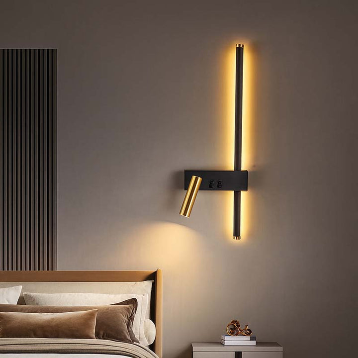 Modern wall sconce on a gray wall with a bed and nightstand in the foreground