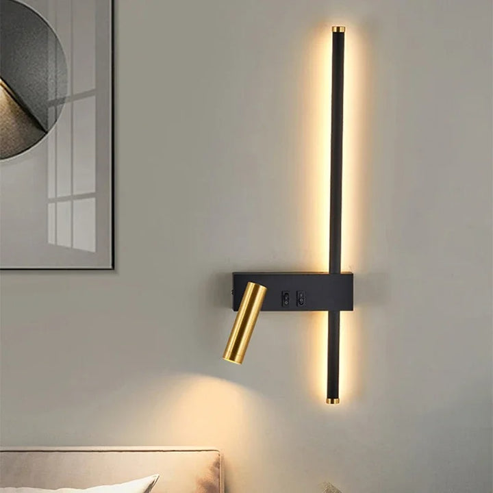 Modern wall-mounted light fixture with black and gold design on a neutral wall.