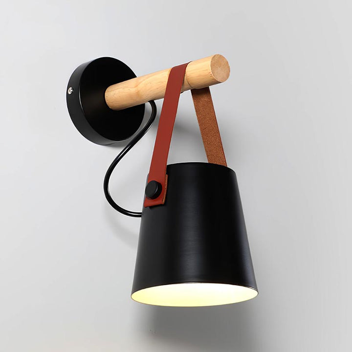 Wall-mounted lamp with black shade, wooden arm, and leather strap on a gray background