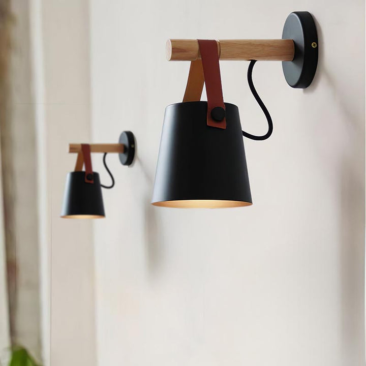 Modern wall-mounted lamp with black shade and wooden accents on a white wall.