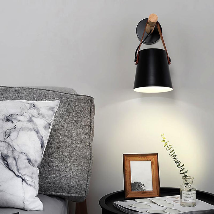 Black wall sconce lamp on a gray wall above a table with decor items.