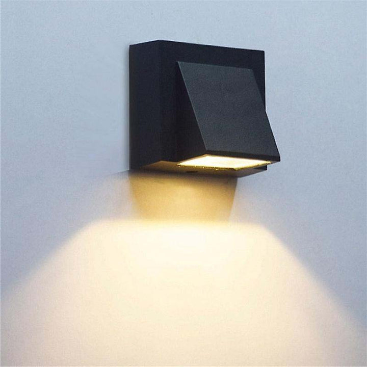 Outdoor black square LED wall light fixture on a light blue background