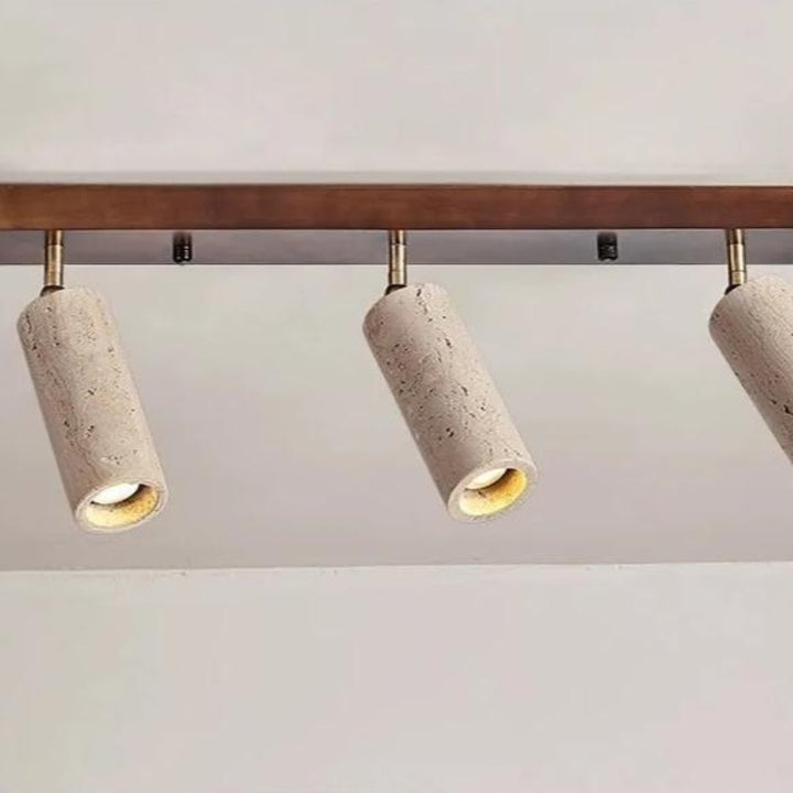 Track light fixture with concrete cylindrical lights on a plain background