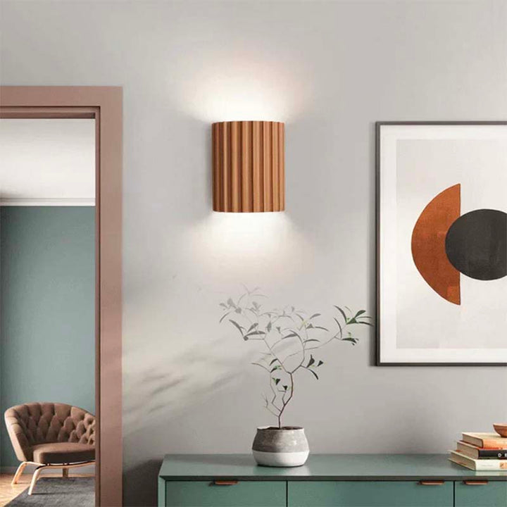 Modern interior design with a wall light, abstract art, and a chair.