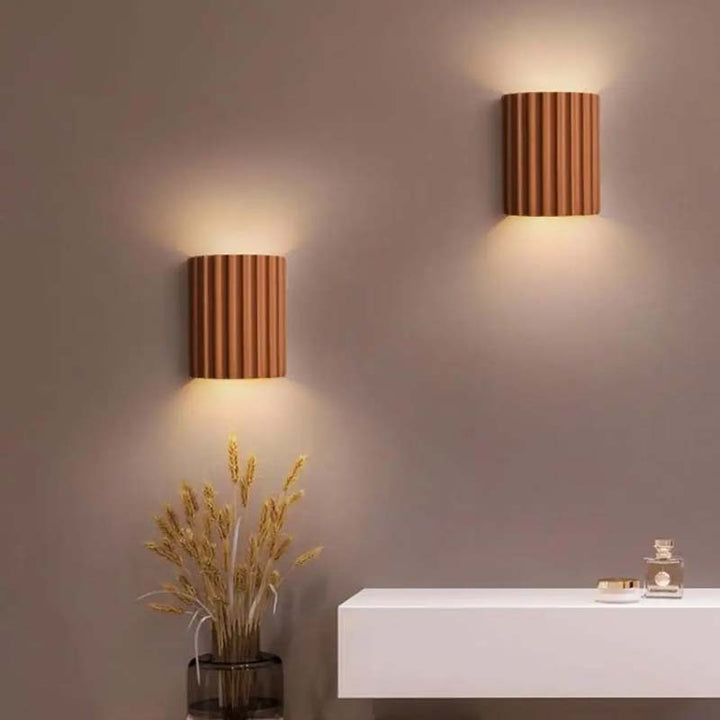 Two wooden wall sconces on a neutral wall with a white console table and decorative items.