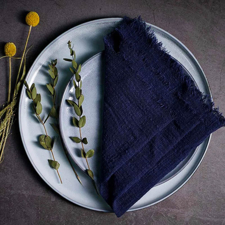 Navy blue cotton gauze napkin folded on ceramic plate with botanical accents, 41 × 41cm – soft and elegant for Scandinavian-style tables.