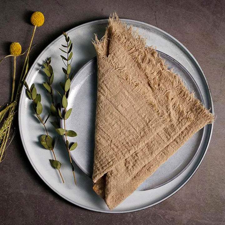 Brown cotton gauze napkin folded on ceramic plate with botanical accents, 41 × 41cm – soft and elegant for Scandinavian-style tables.