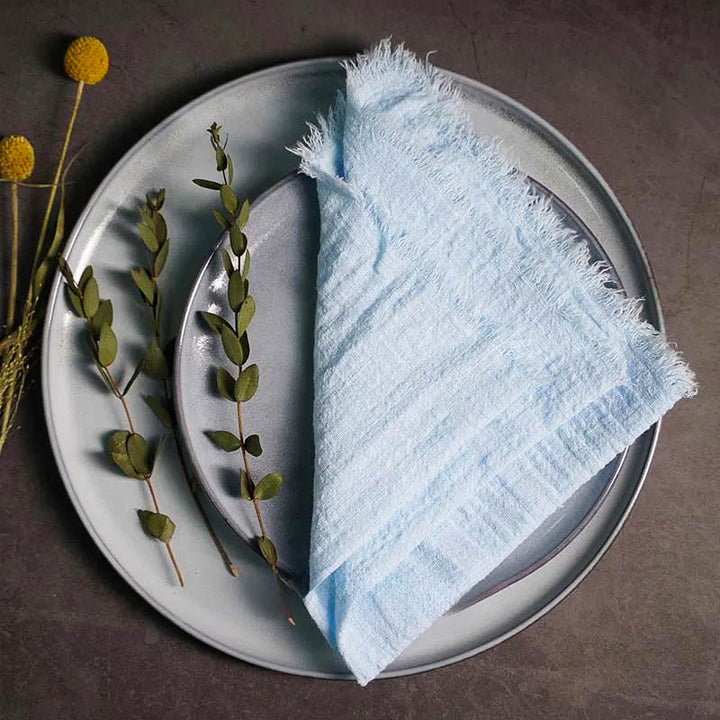 Light blue cotton gauze napkin folded on ceramic plate with botanical accents, 41 × 41cm – soft and elegant for Scandinavian-style tables.