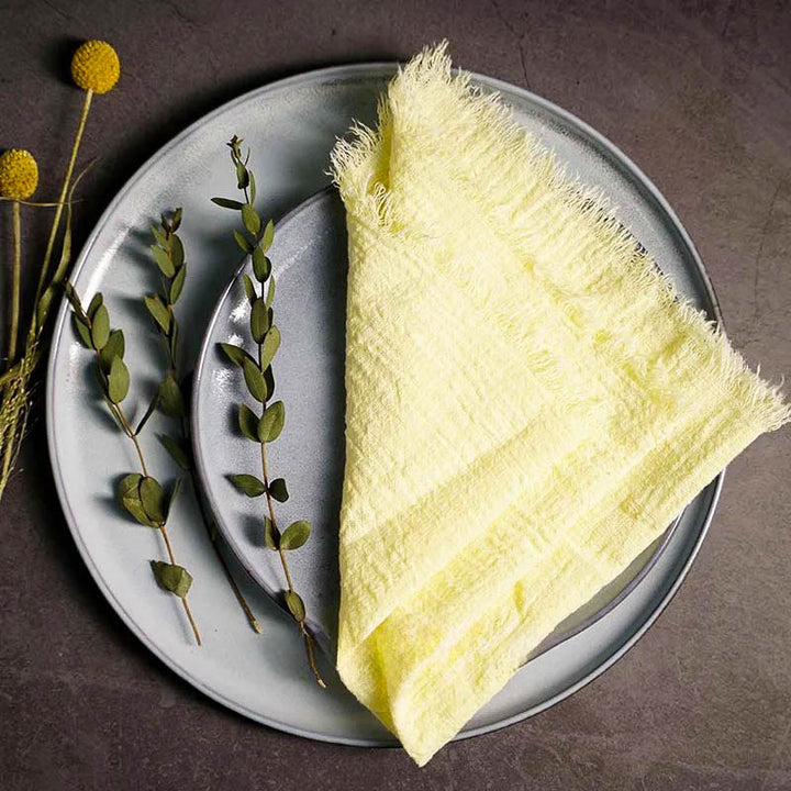 Yellow cotton gauze napkin folded on ceramic plate with botanical accents, 41 × 41cm – soft and elegant for Scandinavian-style tables.