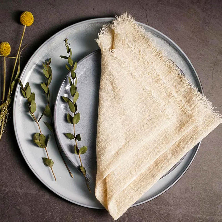 Beige cotton gauze napkin folded on ceramic plate with botanical accents, 41 × 41cm – soft and elegant for Scandinavian-style tables.