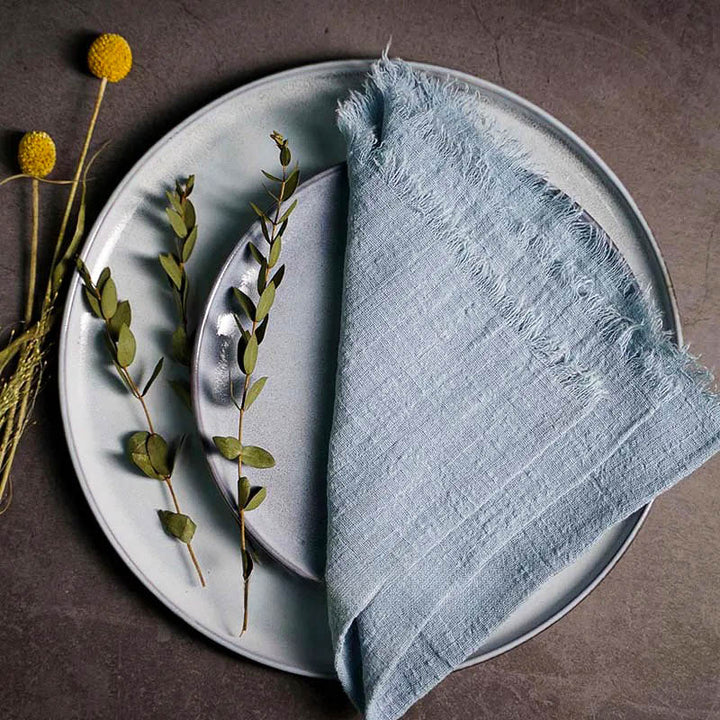 Light blue cotton gauze napkin folded on ceramic plate with botanical accents, 41 × 41cm – soft and elegant for Scandinavian-style tables.