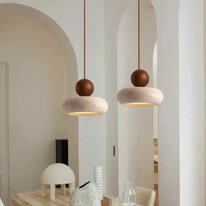 Pair of NATUR pendant lights with warm glow and wooden detail hanging in modern dining area