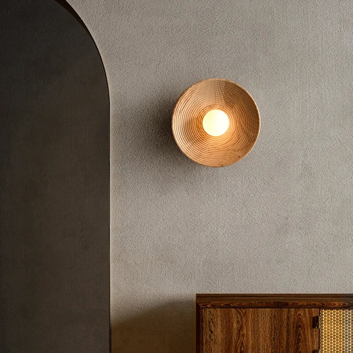 Close-up of SFARISK lamp casting a soft ambient glow against a textured grey wall in a modern home.