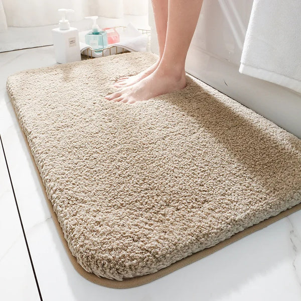 Beige bath mat on a bathroom floor with a person stepping onto it.