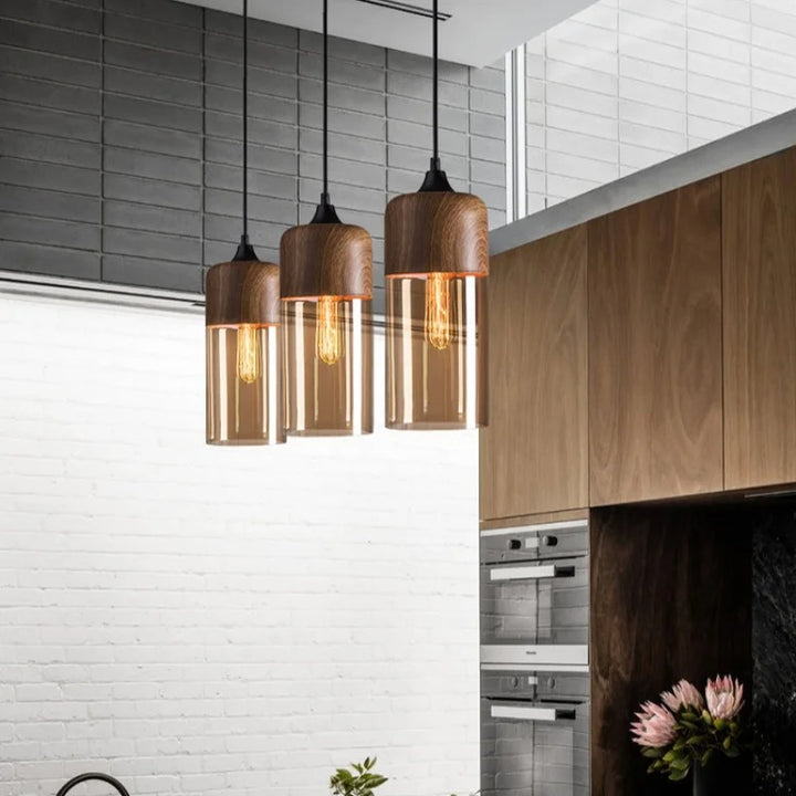 Three nordic pendant lights hanging in a modern kitchen with white tiled walls and wooden cabinets.