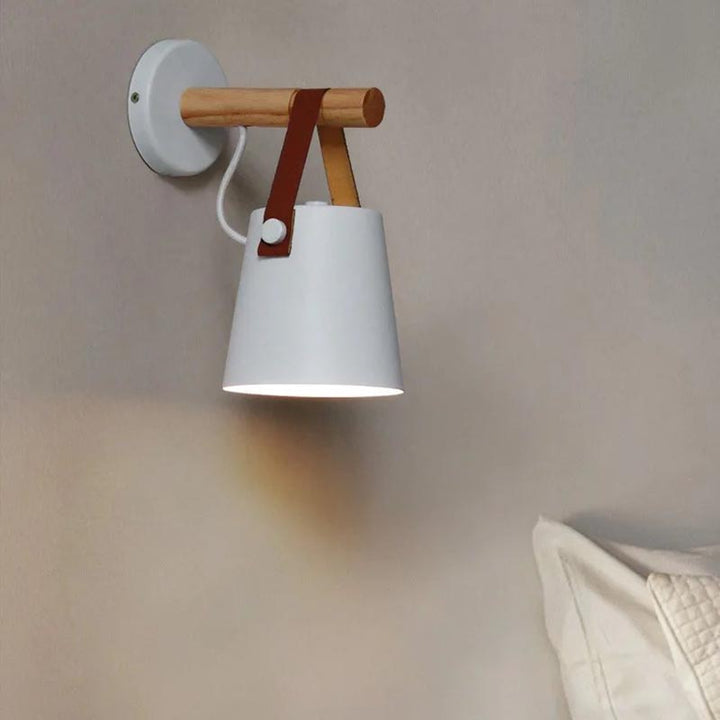 Wall-mounted lamp with white shade and wooden arm on a neutral wall.