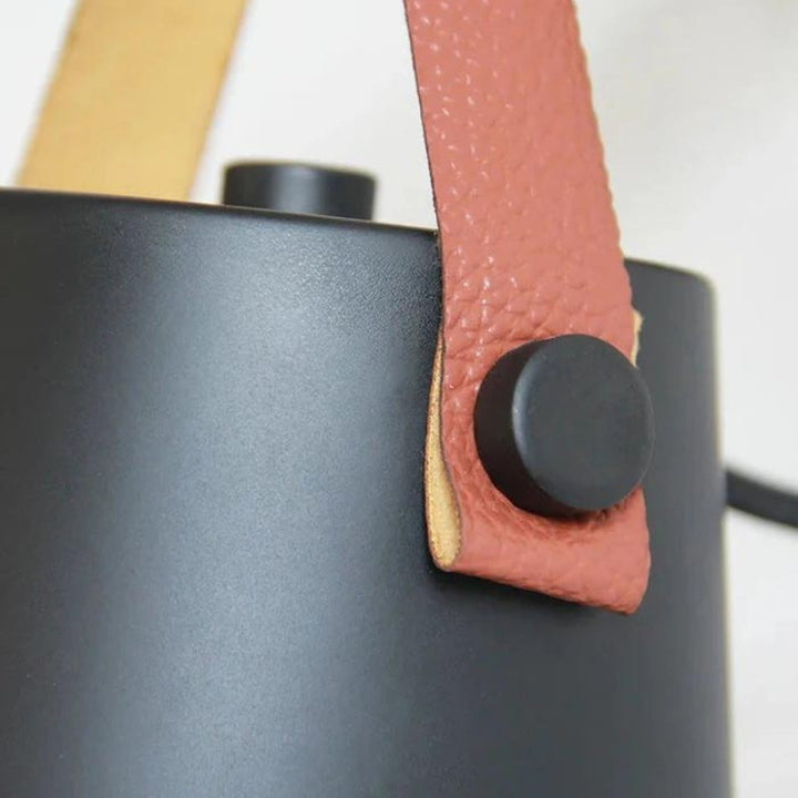 Black kettle with a pink leather handle on a white background