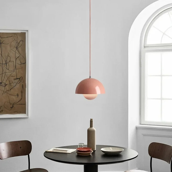 Dining room with a pink pendant light, round table, and chairs.