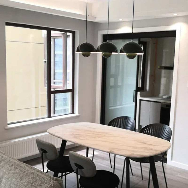 Modern dining room with a wooden table and black chairs near a large window.