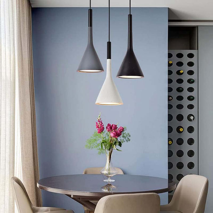 Modern dining area with round table, chairs, and pendant lights against a blue wall.
