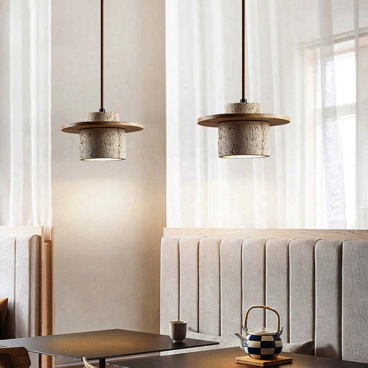 Two modern pendant lights hanging above a dining table with a checkered lamp and cup.