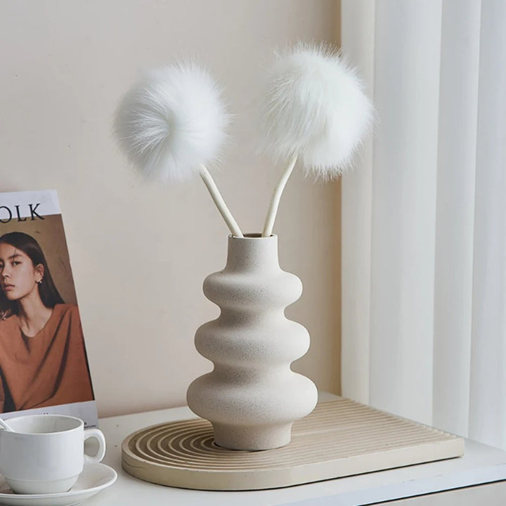 Minimalist Nordic ceramic vase with sculptural shape, styled with faux pom-pom stems on bedside table