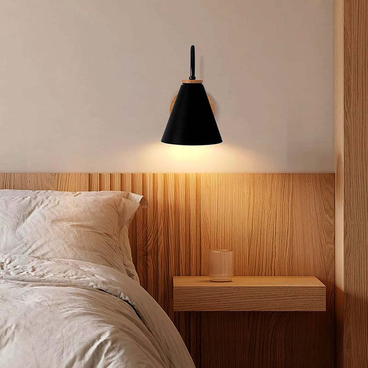 Black wall-mounted nordic lamp above a bed in a bedroom setting