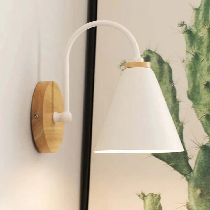 Wall-mounted nordic lamp with wooden base and white shade next to a cactus plant