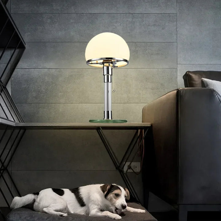 Modern Bauhaus bedside lamp with glass base and chrome stand beside sofa