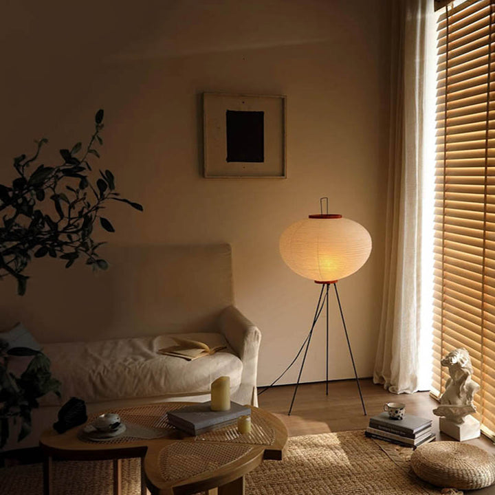 Soft rice paper floor lamp casting ambient glow in serene Japandi-style room with rattan rug.