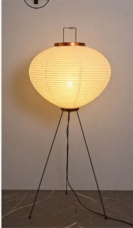 Minimalist paper floor lamp with curved rice paper shade and slim metal legs, ideal for modern UK Scandi-inspired living rooms.