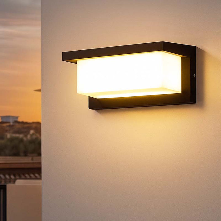 Modern outdoor wall light fixture on a wall with a sunset view in the background.