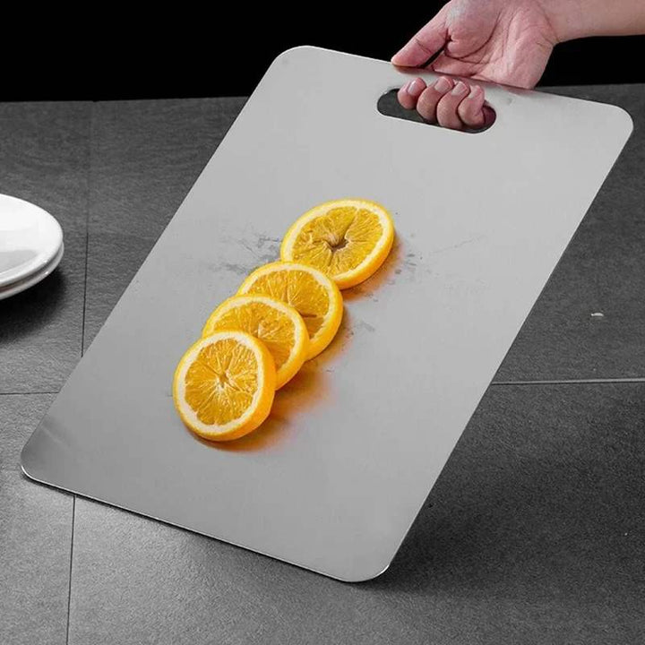 Holding stainless steel cutting board with sliced oranges – hygienic, durable, modern kitchen essential