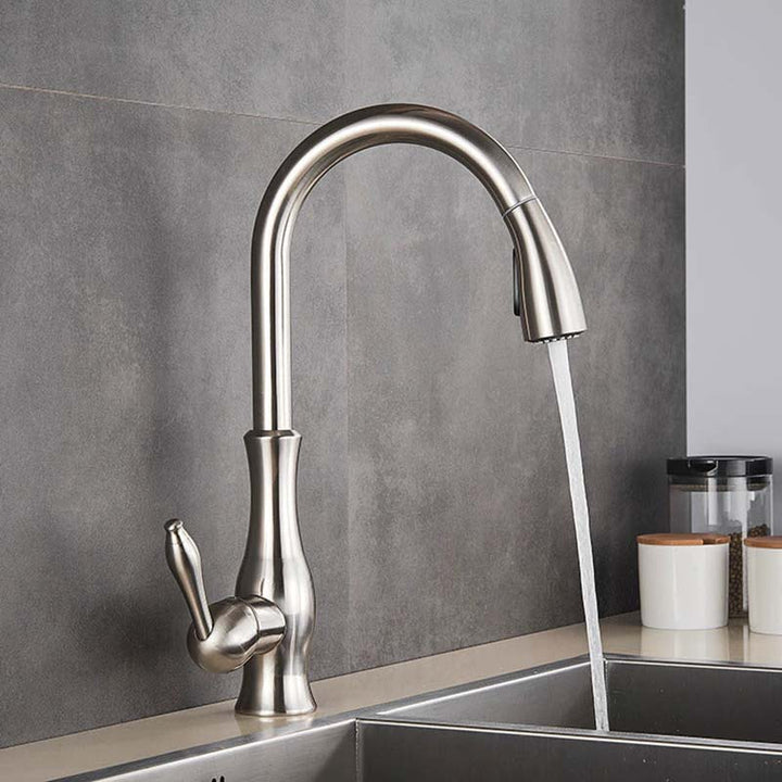 Modern Pull-Out kitchen faucet with water flowing into a sink against a gray tiled wall.