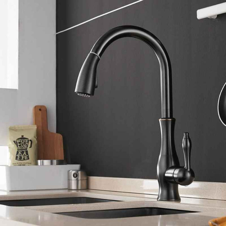 Black kitchen faucet on a modern kitchen counter with a dark backsplash.