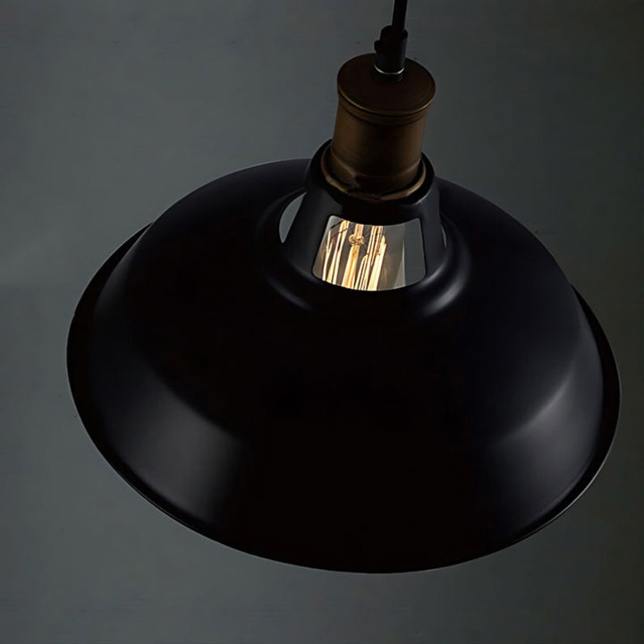 Black pendant light with a visible bulb against a dark background
