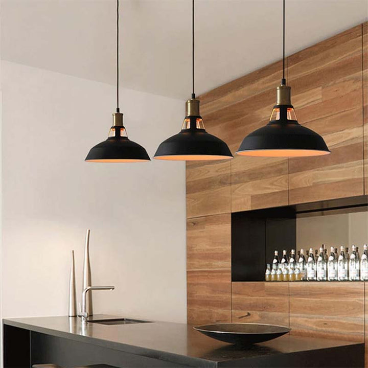 Modern UK kitchen with black industrial pendant lights, stainless steel sink, and wooden wall.